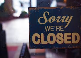 A rustic 'Sorry We're Closed' sign displayed on a shop door, atmospheric lighting.